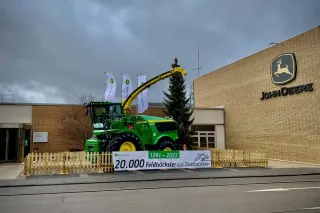 Samojízdná řezačka John Deere vystavená před závodem.