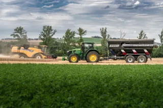 Traktor s překládacím vozem Perard vedle sklízecí mlátičky.
