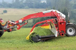 Červený řádkovač Pöttinger MERGENTO na louce.