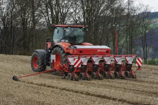 Traktor se secím strojem Kverneland Optima na poli.