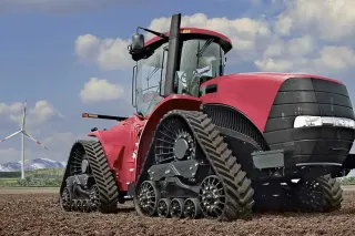 Červený pásový traktor při práci na poli