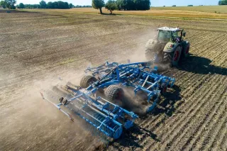 Traktor s modrým kypřičem Lemken Karat při práci na poli