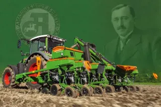 Zeleno-oranžový secí stroj Amazone na poli před historickým portrétem