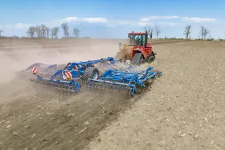 Traktor s modrým kypřičem Köckerling na poli