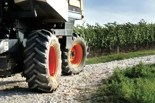 Pneumatiky zemědělského stroje na kamenité cestě vedle vinice