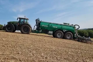 Traktor se zelenou cisternou Samson na poli
