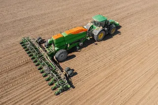 Traktor se širokým secím strojem Amazone na poli