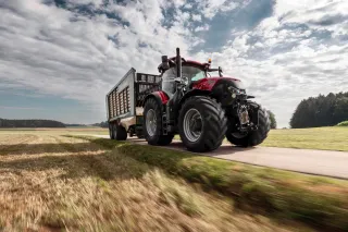 Červený traktor Case IH Optum s přívěsem na silnici
