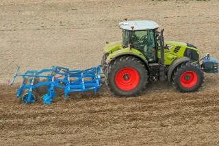 Traktor s modrým radličkovým kypřičem Lemken Karat na poli