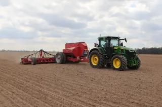 Zelený traktor s červeným secím strojem Horsch na poli