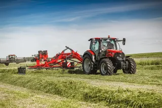 Traktor s červeným shrnovačem SIP na louce