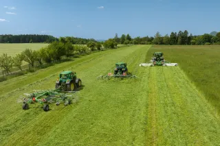Tři traktory se stroji SaMASZ při práci na louce