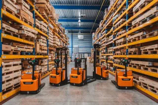Oranžové skladové vozíky Doosan mezi regály s náhradními díly