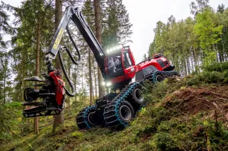 Červený lesní harvestor Komatsu ve svahu mezi stromy