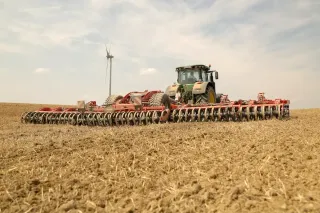 Traktor s širokým podmítačem Kuhn Optimer na poli