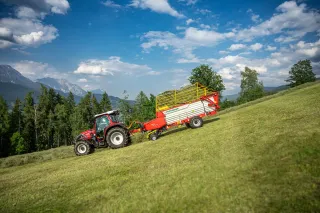 Traktor se sběracím vozem Pöttinger na horské louce