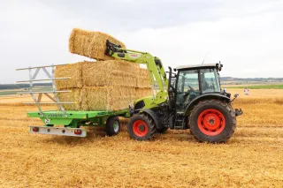 Traktor Claas AXOS s čelním nakladačem při manipulaci s balíky
