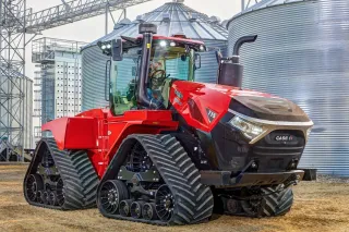 Červený pásový traktor Case IH Quadtrac před obilními sily