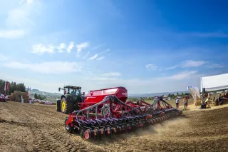Zelený traktor s červeným secím strojem Horsch při polní ukázce
