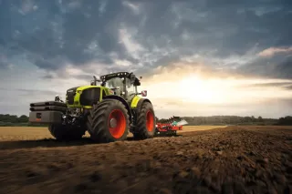 Traktor CLAAS s pluhem při práci na poli