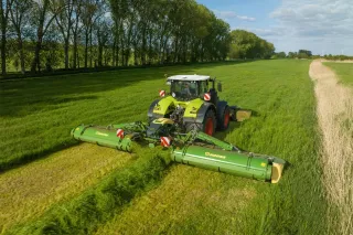 Traktor s žací kombinací Krone na louce