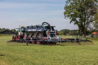 Traktor s cisternou a širokým aplikátorem hnojiv Vogelsang BlackBird na louce