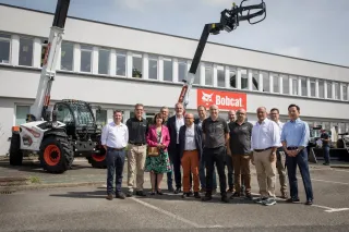 Skupina lidí před závodem Bobcat vedle teleskopického manipulátoru