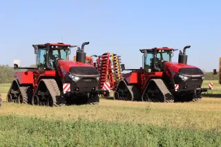 Dva červené pásové traktory Case IH Quadtrac 715 na poli.