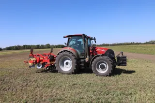 Červený traktor Case IH Vestrum s neseným strojem při práci na poli.