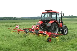 Červený obraceč ROZMITAL za traktorem při obracení sena