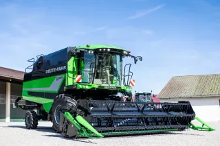 Zelená sklízecí mlátička Deutz-Fahr C6305 před hospodářskou budovou