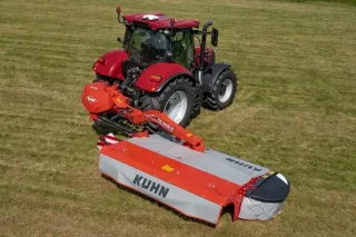 Červený traktor s žacím strojem Kuhn FC 3515 R na louce