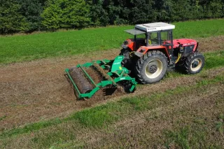 Červený traktor s diskovým podmítačem SUKOV na poli