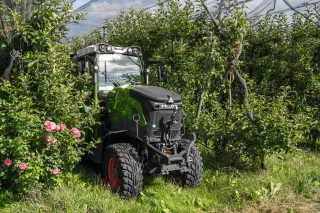 Zelený elektrický traktor Fendt mezi ovocnými stromy