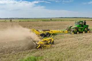 Pásový traktor táhne žlutý diskový podmítač BEDNAR po poli