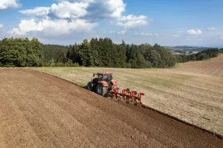 Traktor s neseným pluhem Pöttinger Servo 3000 při orbě pole