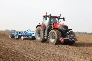 Červený traktor Case IH Optum s modrým diskovým nářadím na poli