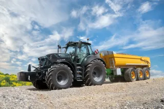 Černý traktor Deutz-Fahr se žlutým přívěsem