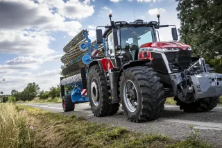 Traktor Massey Ferguson 9S s modrým nářadím na silnici