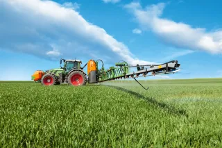 Traktor s postřikovačem Amazone stříká porost na poli