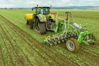 Traktor s pásovým podvozkem táhne stroj pro pásové zpracování půdy