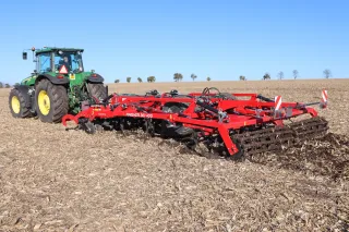 Zelený traktor John Deere s červeným kypřičem SMS CZ Finisher na poli