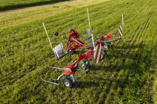Červený obraceč Massey Ferguson na louce