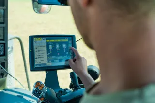 Obsluha nastavuje dotykový displej secího stroje v kabině traktoru