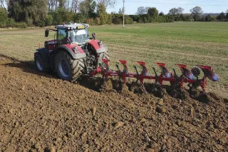 Traktor s červeným pluhem SUKOV při orbě