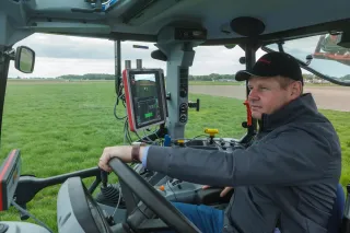 Muž v kabině traktoru u monitoru precizního zemědělství.