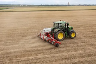 Traktor s rotační plečkou Pöttinger při práci na poli