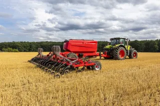 Traktor Claas táhne secí stroj Horsch Sprinter přes strniště