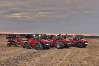 Tři červené traktory Case IH se secími stroji na poli