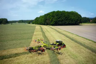 Čtyřrotorový shrnovač Claas Liner s traktorem na louce
